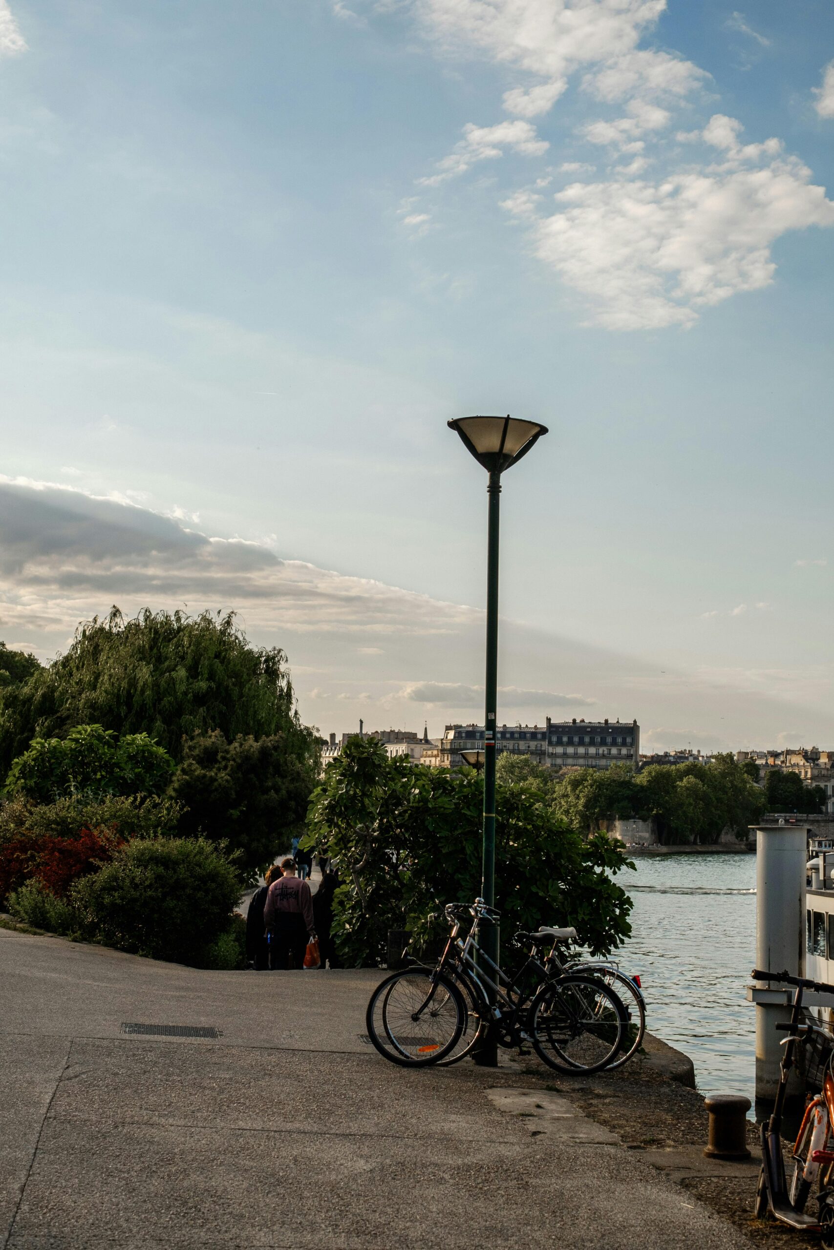 Peaceful riverside scene with bicycles and street lamp during sunset. Ideal for leisure and travel concepts.